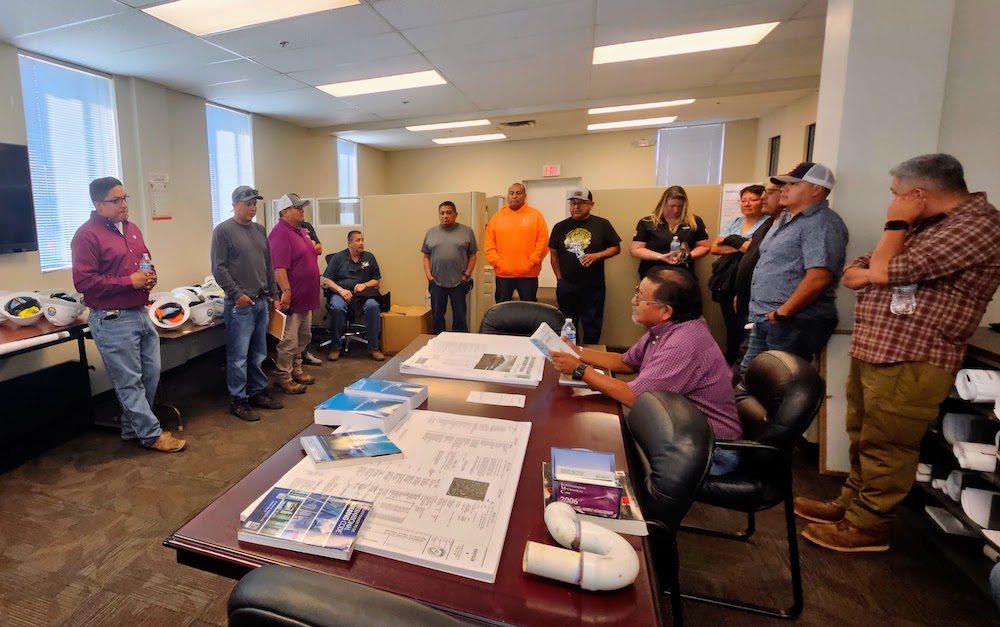 Members of the Southwest Tribal Housing Alliance gather for training on building code implementation at Gila River Housing offices. This collaboration exemplifies how Native communities are developing construction expertise that honors both modern safety standards and traditional Indigenous building techniques. As tribes reclaim control over construction practices, these discussions ensure buildings meet community needs while preserving cultural identity. (Credit: David Jackson)